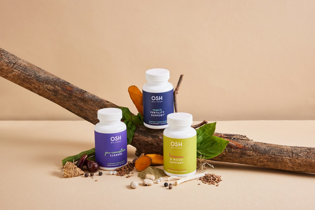 Frascos de suplementos naturais com ingredientes botânicos sobre um tronco de madeira.