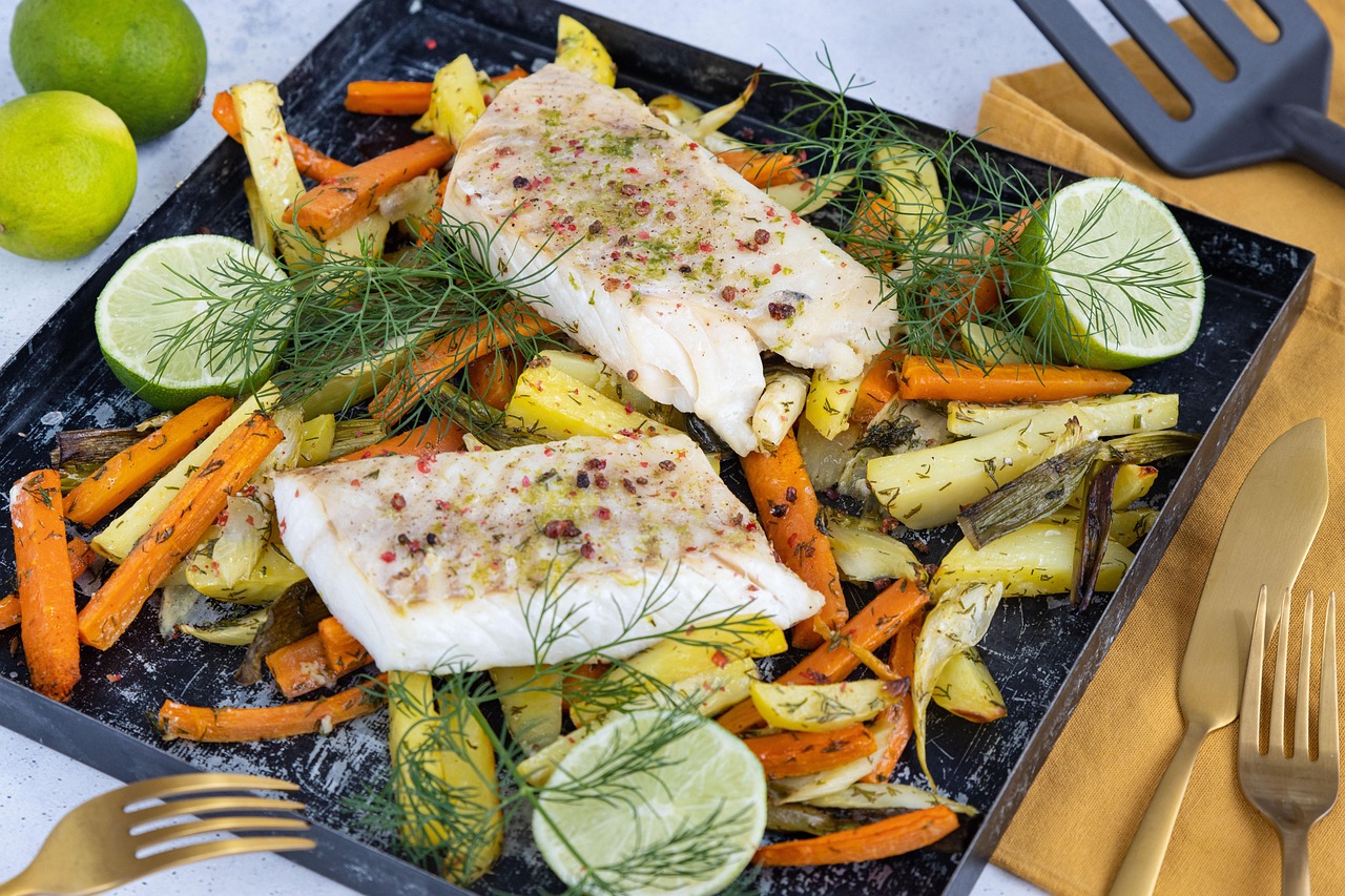 Prato colorido com filé de peixe, vegetais assados, limão e ervas frescas em uma refeição equilibrada.