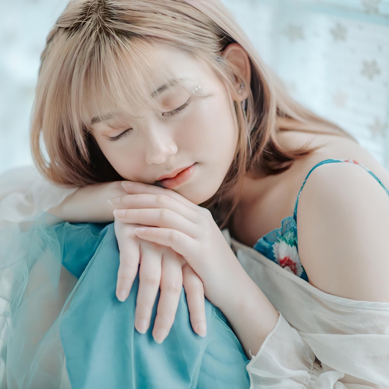 Mulher jovem com os olhos fechados e mãos cruzadas, descansando pacificamente.