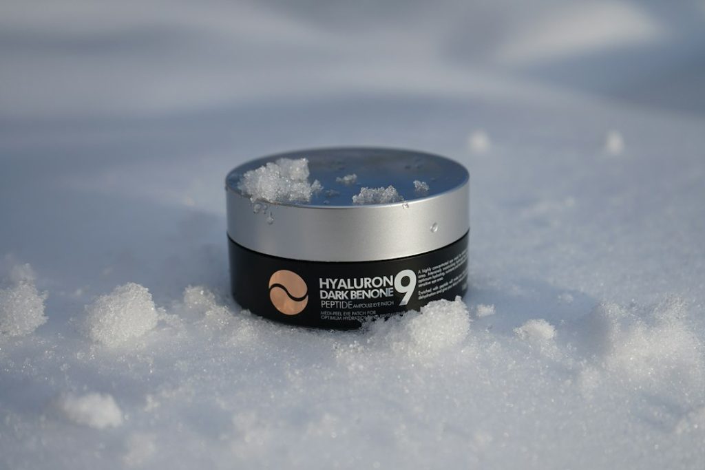 Frasco de creme hidratante apoiado sobre a neve em dia frio de inverno