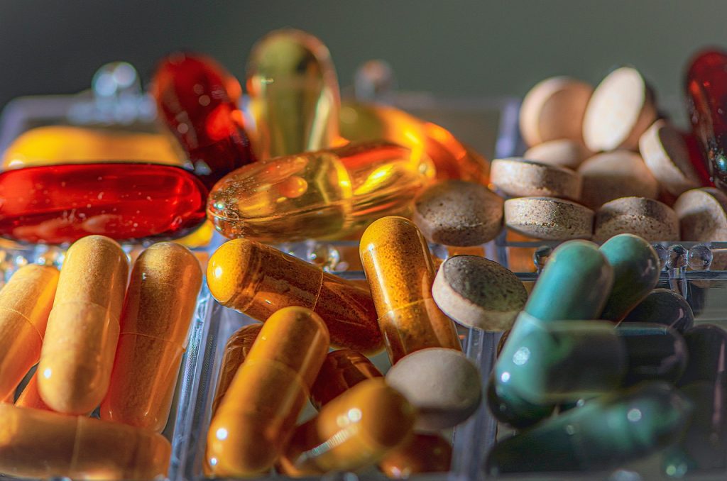 Cápsulas e comprimidos coloridos de suplementos organizados em um porta-comprimidos.