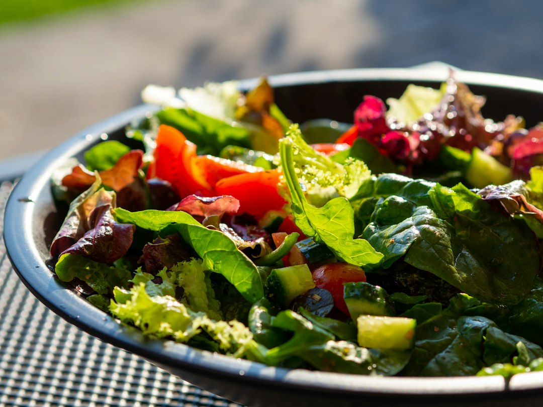 Tigela com salada fresca contendo folhas verdes, tomates e pepinos.