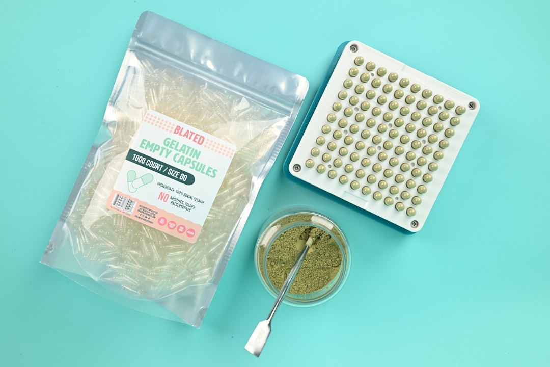 Kit de encapsulamento com cápsulas gelatinosas, pó verde em frasco e espátula em bancada azul