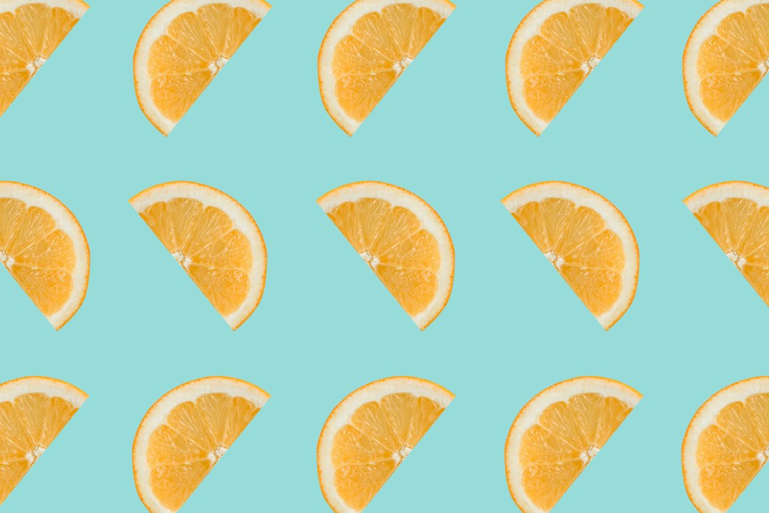 Fatias de frutas cítricas em padrão repetido sobre fundo azul-claro.
