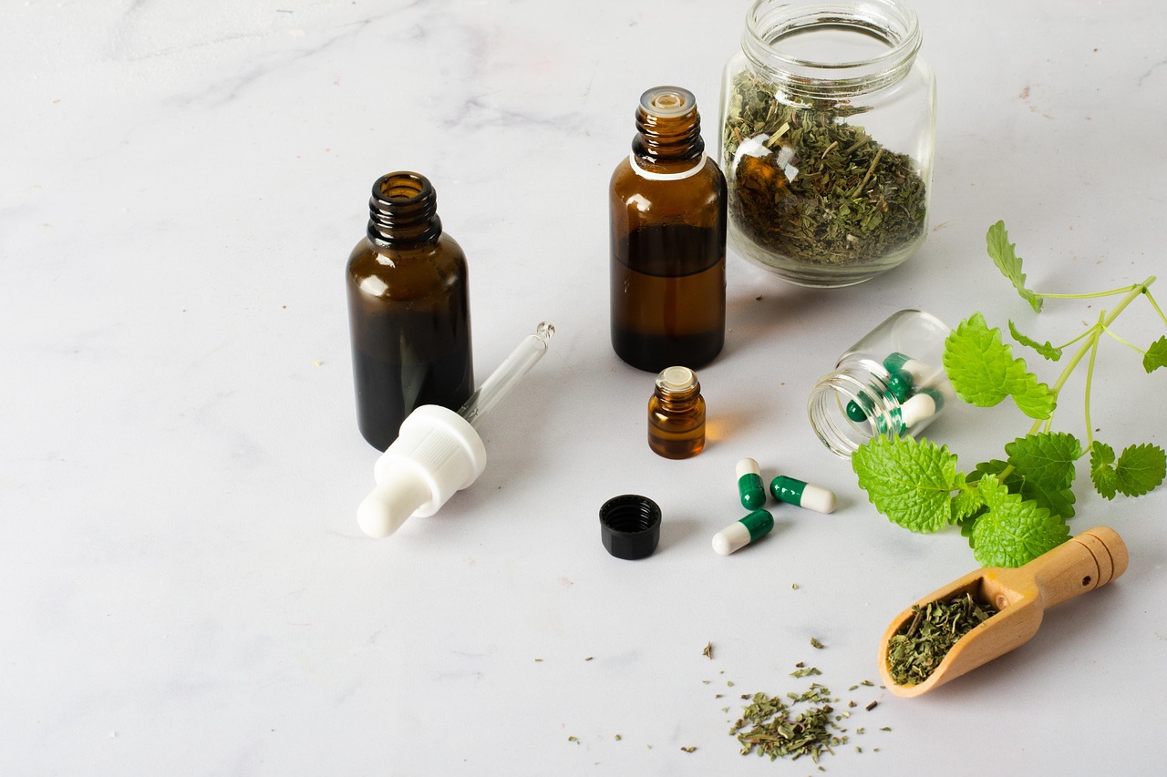 Frascos de vidro âmbar, cápsulas fitoterápicas e ervas medicinais sobre bancada.