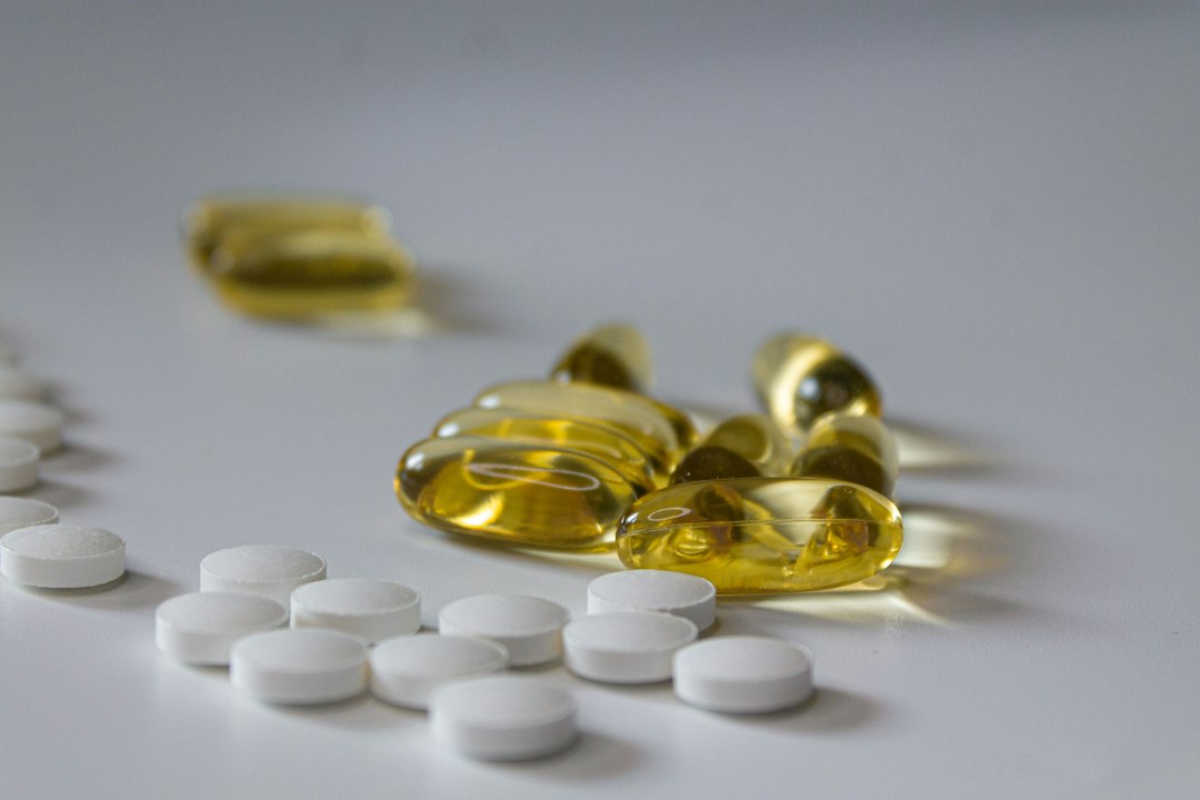 Capsulas de oleo e comprimidos brancos de suplementos alimentares sobre fundo branco